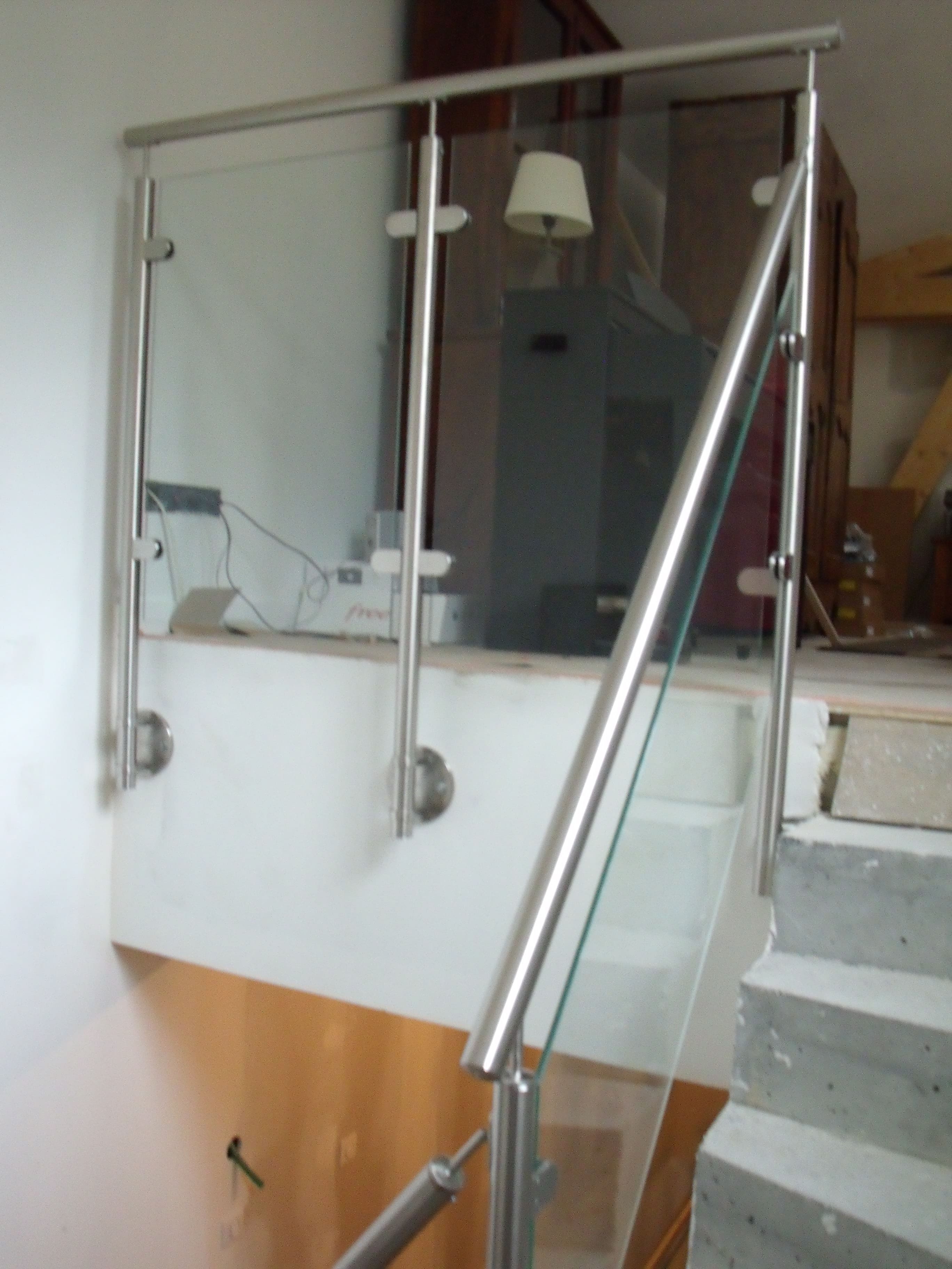 Fabrication et pose d'un garde-corps vitré en inox sur mesure pour un escalier intérieur. Les poteaux et la main courante sont en tube inox brossé rond. Le remplissage est en verre feuilleté découpé sur mesure. Il protégé la montée d'escalier du rez de chaussé au deuxième étage, ainsi que les deux paliers. Garde-corps réalisé et installé par l'entreprise Claude Jeandin métallerie.