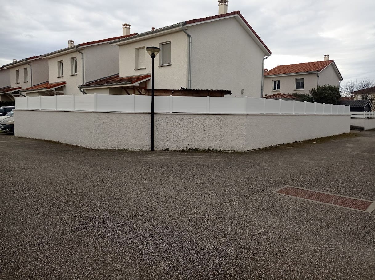 Pose d'un pare vue sur muret en lames pvc. Les poteaux sont en aluminium ral 9010 et le remplissage composé de cinq rangées de lames horizontales blanches. La hauteur totale est de 200 cm. Pare vue installé par l'entreprise Claude Jeandin métallerie.