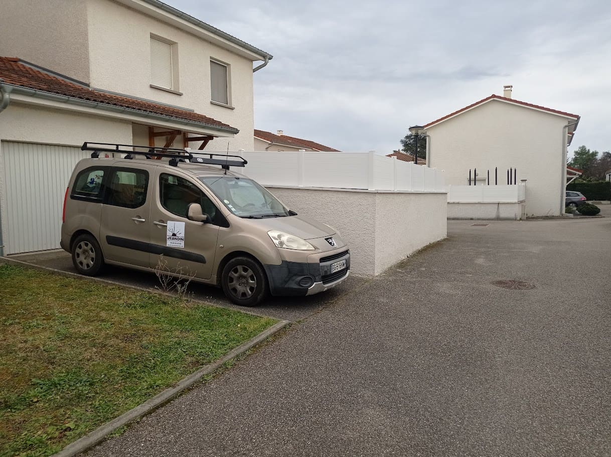 Pose d'un pare vue sur muret en lames pvc. Les poteaux sont en aluminium ral 9010 et le remplissage composé de cinq rangées de lames horizontales blanches. La hauteur totale est de 200 cm. Pare vue installé par l'entreprise Claude Jeandin métallerie.