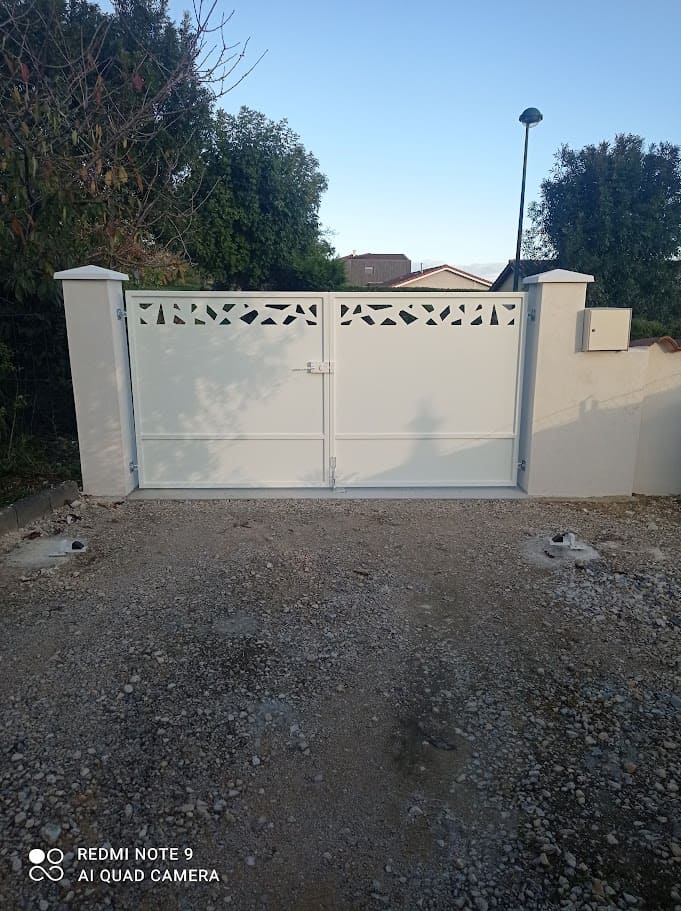 Fabrication et pose d'un portail métallique tôlé plein à deux vantaux. L'ossature est en tube carré, Chaque vantail est constitué de deux tôles, la tôle supérieure et décorée d'un motif en découpe laser. L'ouverture est manuelle, il est équipé d'une serrure décorative de marque LOCINOX. L'ensemble est peint en ral 9010. Portail réalisé par l'entreprise Claude Jeandin métallerie.