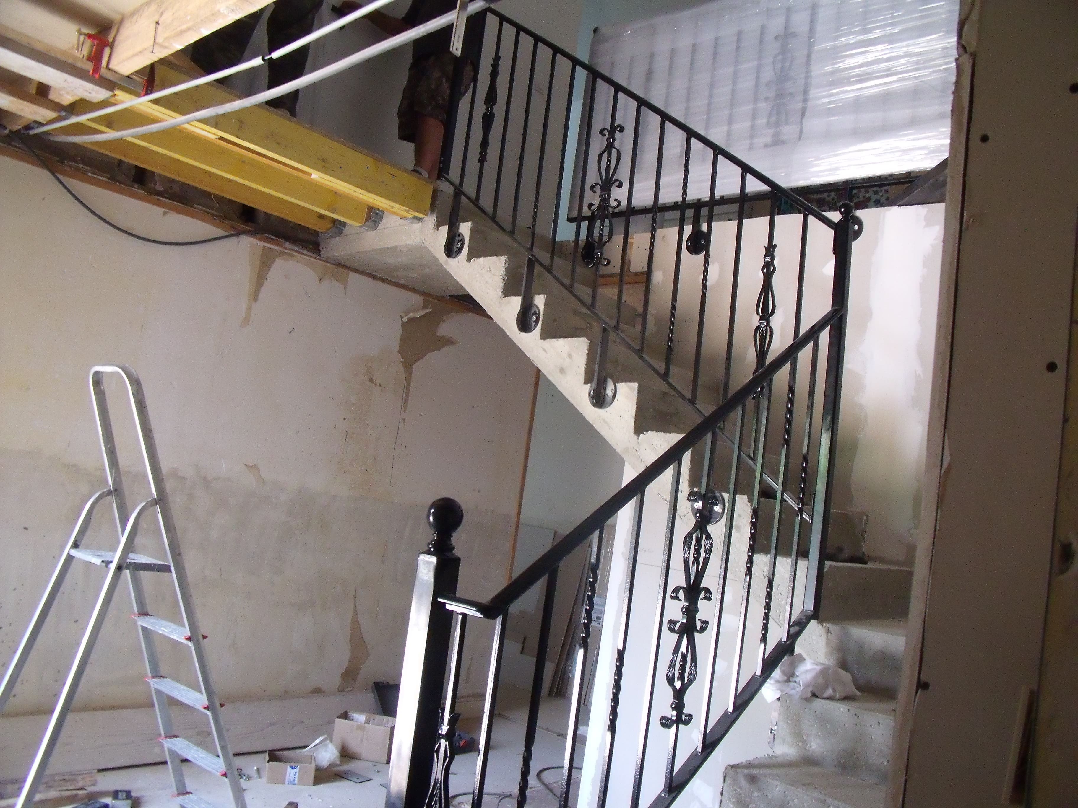 Fabrication et pose d'un garde-corps en fer forgé sur un escalier intérieur. Le barreaudage est verticale, il comprend des barreaux simples en carré de 14, des barreaux torsadés et différents éléments décoratifs forgés. Les poteaux d'angle sont ornés d'une boule décorative, la main courante est moulurée. L'ensemble est peint en ral 9005. Garde-corps réalisé par l'entreprise Claude Jeandin métallerie.